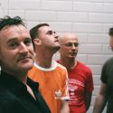 Promo shot of Irish band Blink, the band are standing in front of a wall with while tiles
