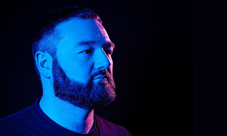 Maddox Jones side view under blue and red lights with a black background