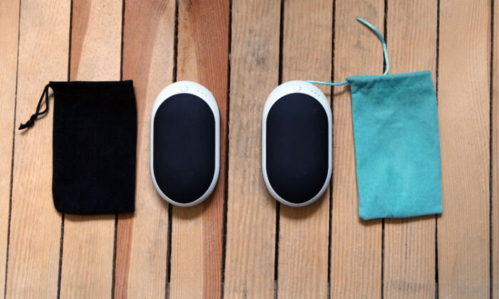 Two Occopa handwarmers with their cloth covers laid out on wood