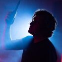 Now Ex in silhouette holding a microphone hanging from above